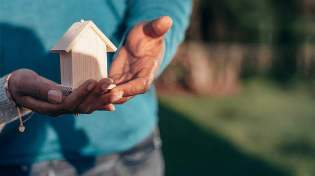 A miniature house being held