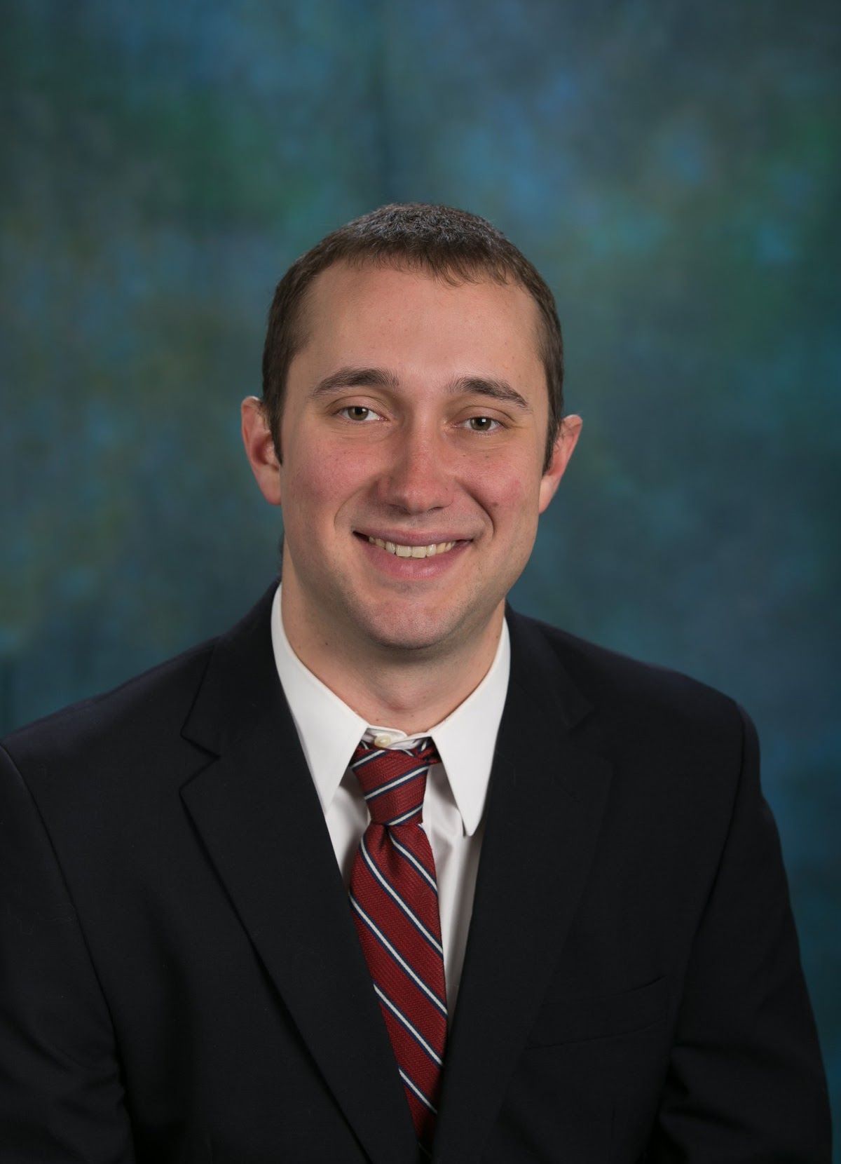 A man in a suit and tie is smiling for the camera