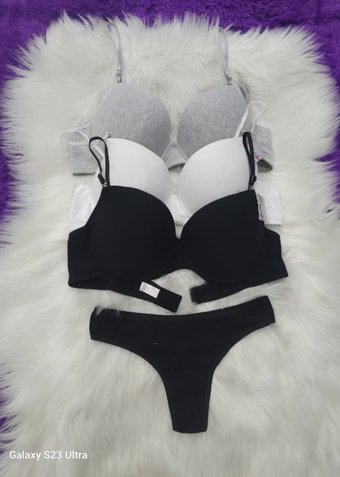 Sujetadores en gris, blanco y negro con tanga negra sobre piel blanca.