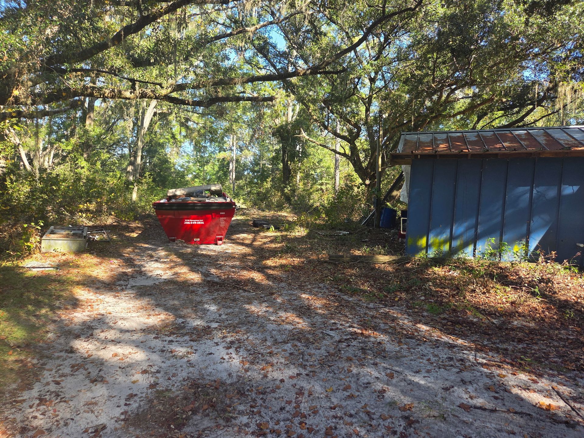 Man in cowboy hat and orange shirt stands by a red dump truck on a street.