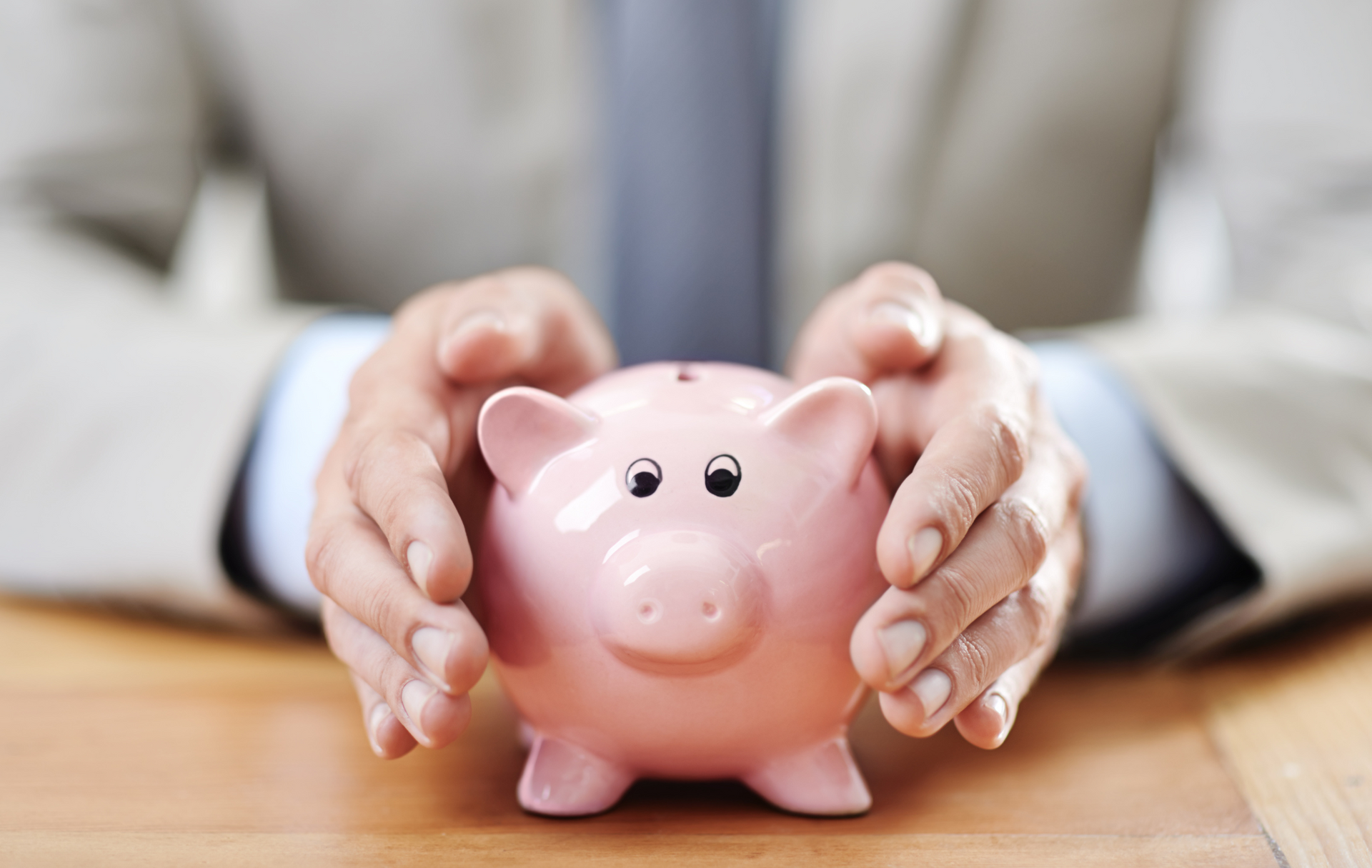 Businessperson protecting a pink piggy bank, symbolising superannuation savings and contribution cap