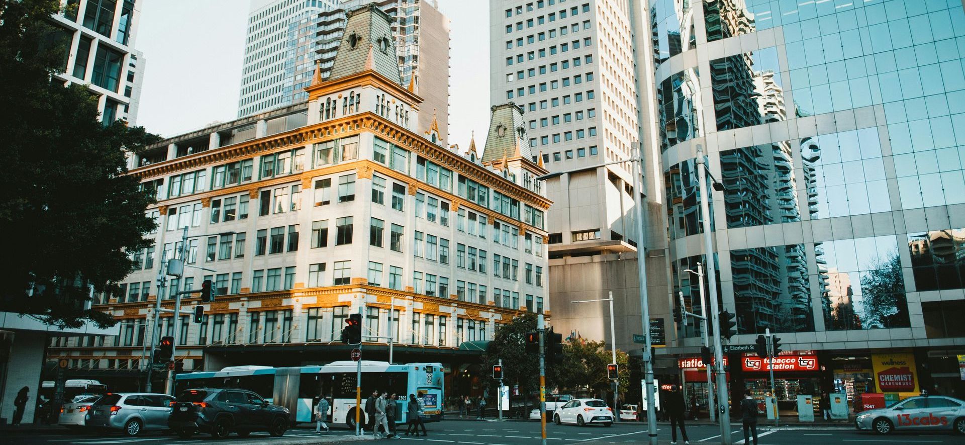 A city street with a lot of tall buildings and cars driving down it.