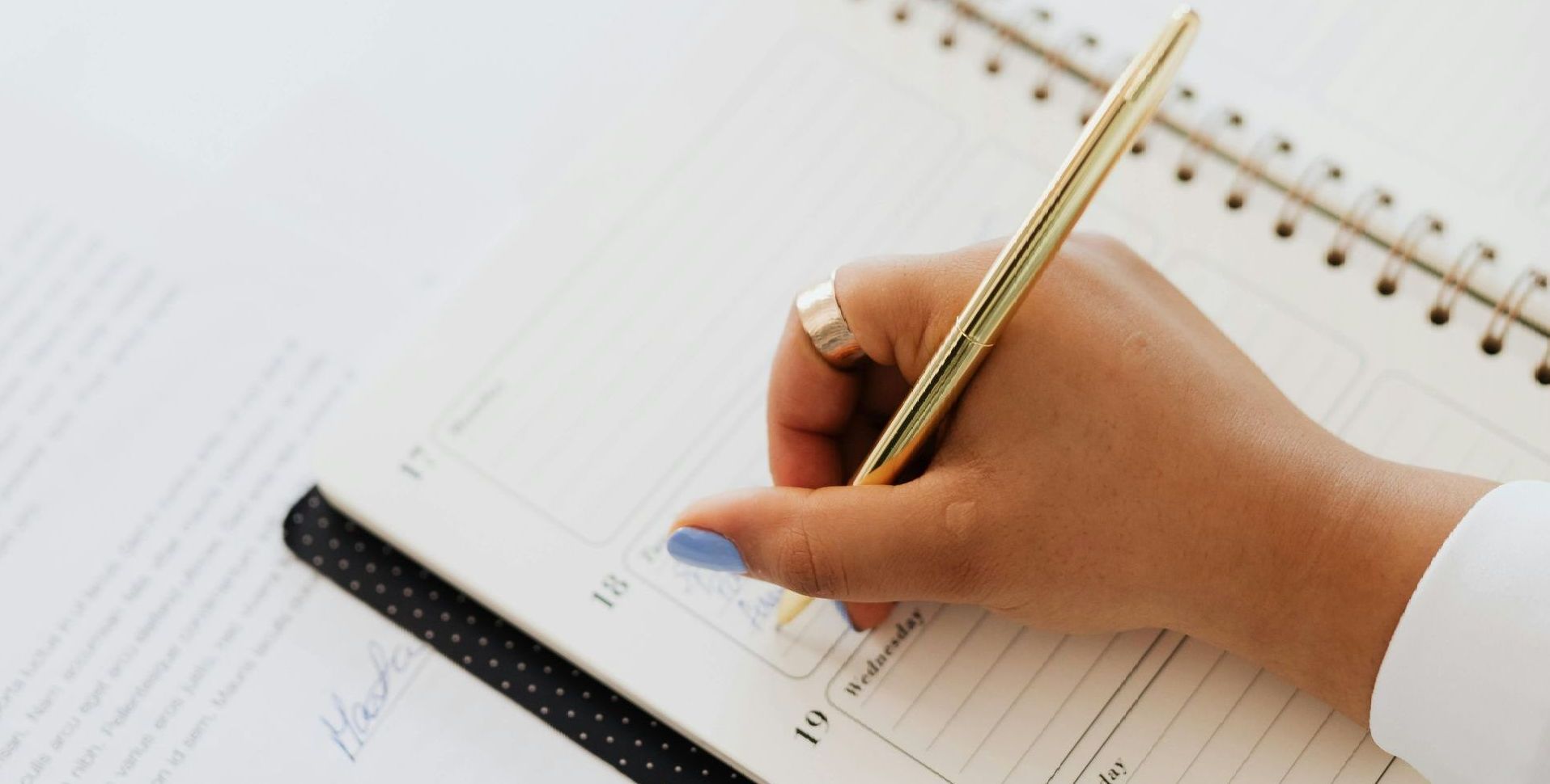 A person is writing in a notebook with a pen.