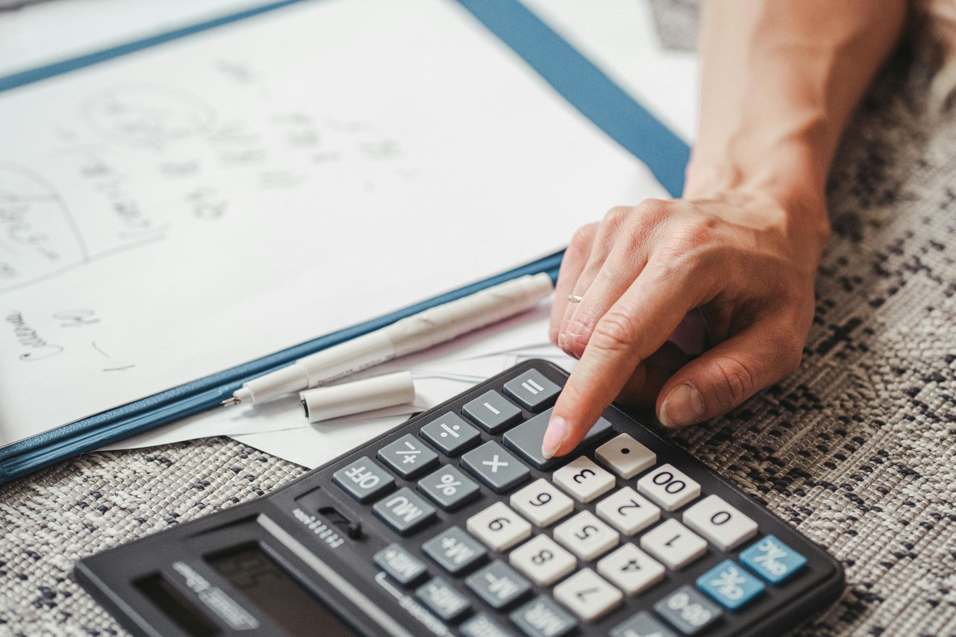 A person is using a calculator on a table.