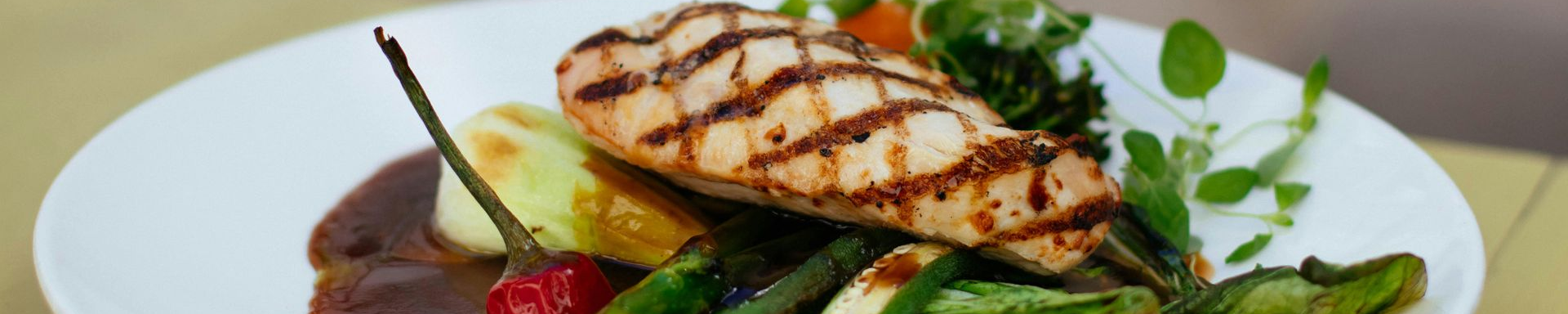 Grilled salmon with vegetables on a white plate.