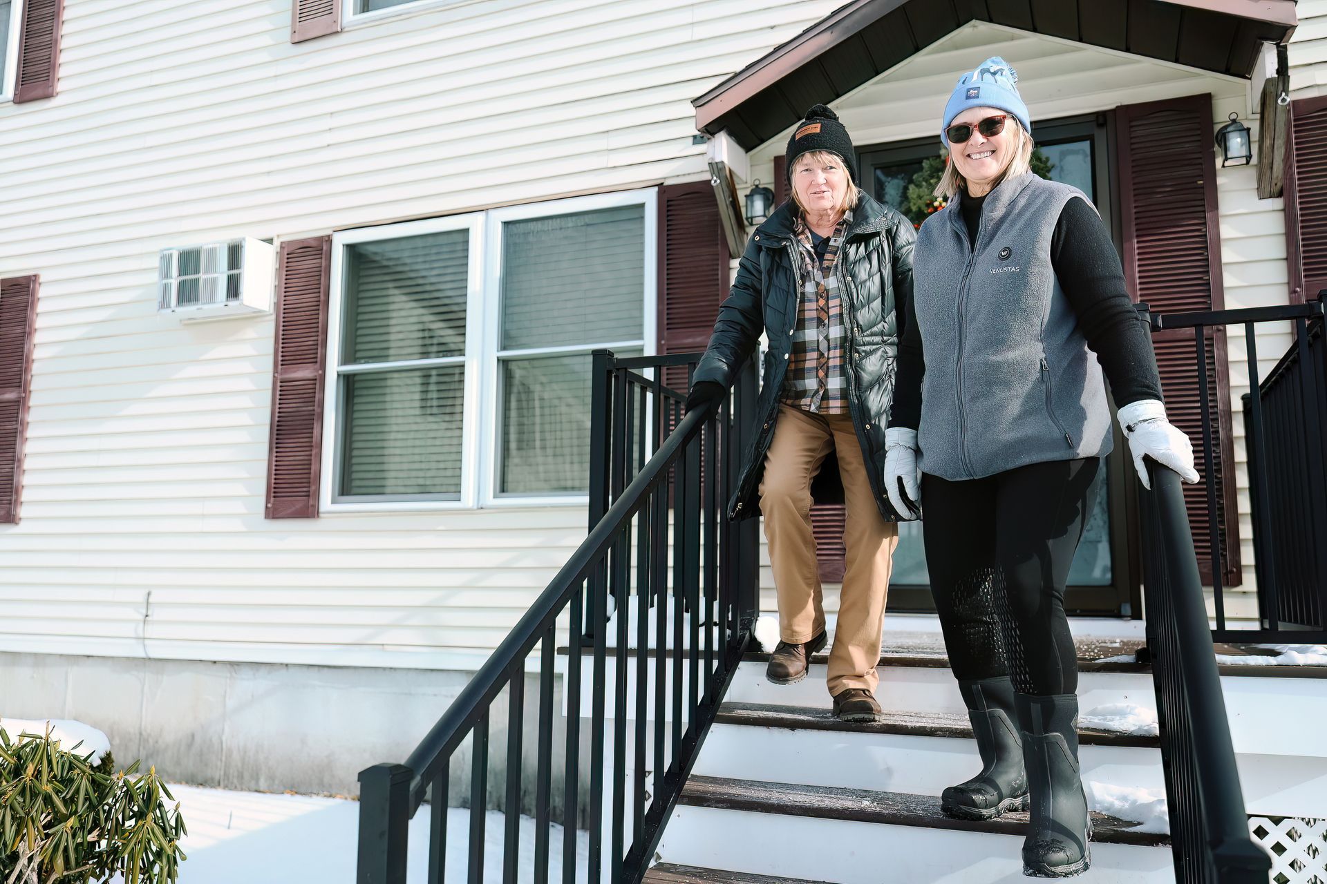 Two people holding a sign thanking Meals on Wheels volunteers. Portraits of seniors are in the background.
