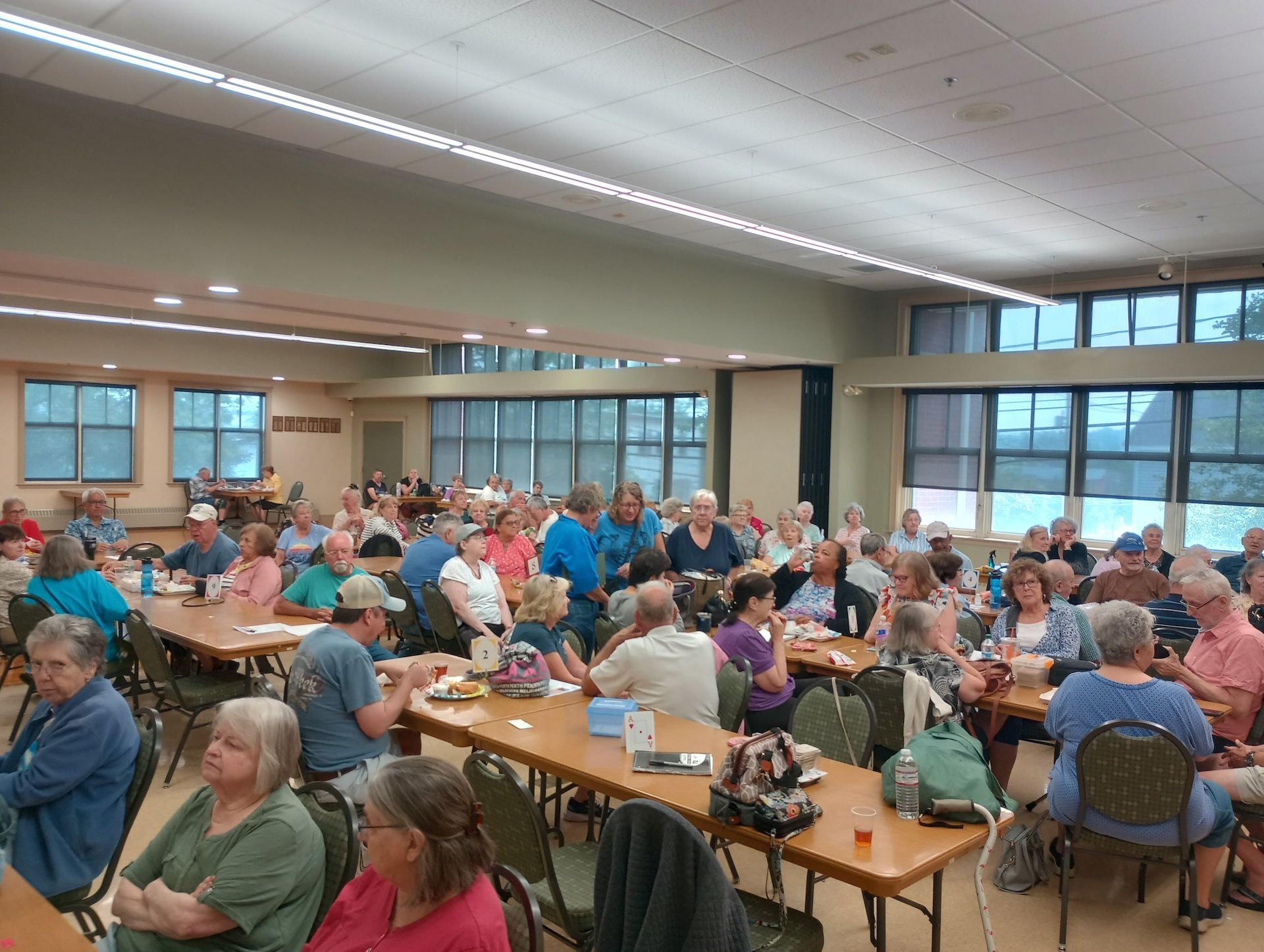 Large room with many people seated at tables; likely a social gathering or event.