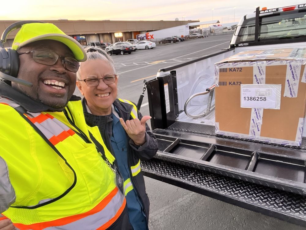 Two men are posing for a picture in front of a truck.