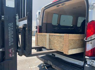 A toyota van with a forklift attached to the back of it.