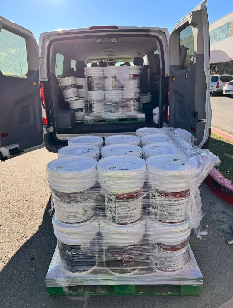 A van filled with buckets of food is parked on the side of the road.