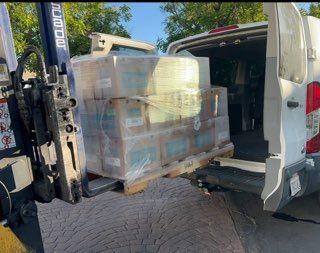 A white van is being loaded with boxes and a forklift.