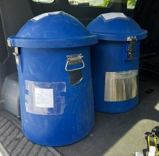Two blue trash cans are in the back of a car