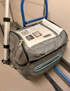 A gray bag is sitting on top of a blue cart.