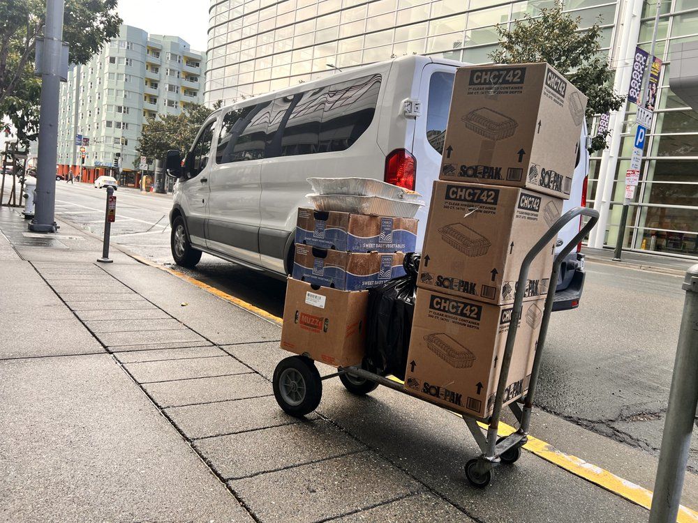 A van is parked on the side of the road with boxes on the back of it.