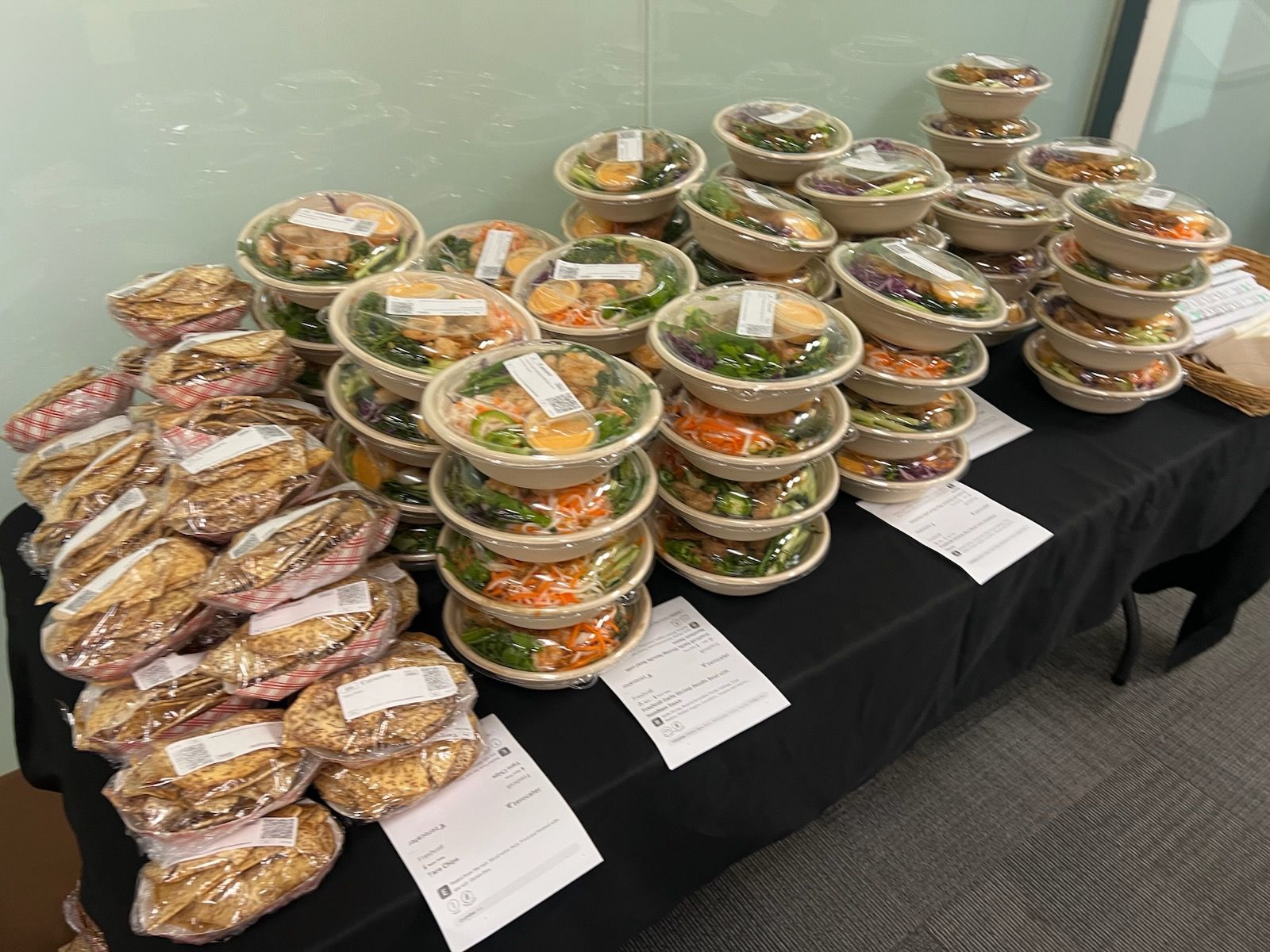 A table topped with lots of bowls of food and sandwiches.