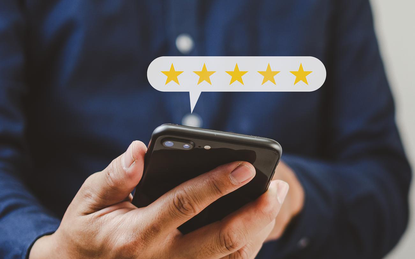 A person holds a smartphone displaying a five-star rating icon in a speech bubble.
