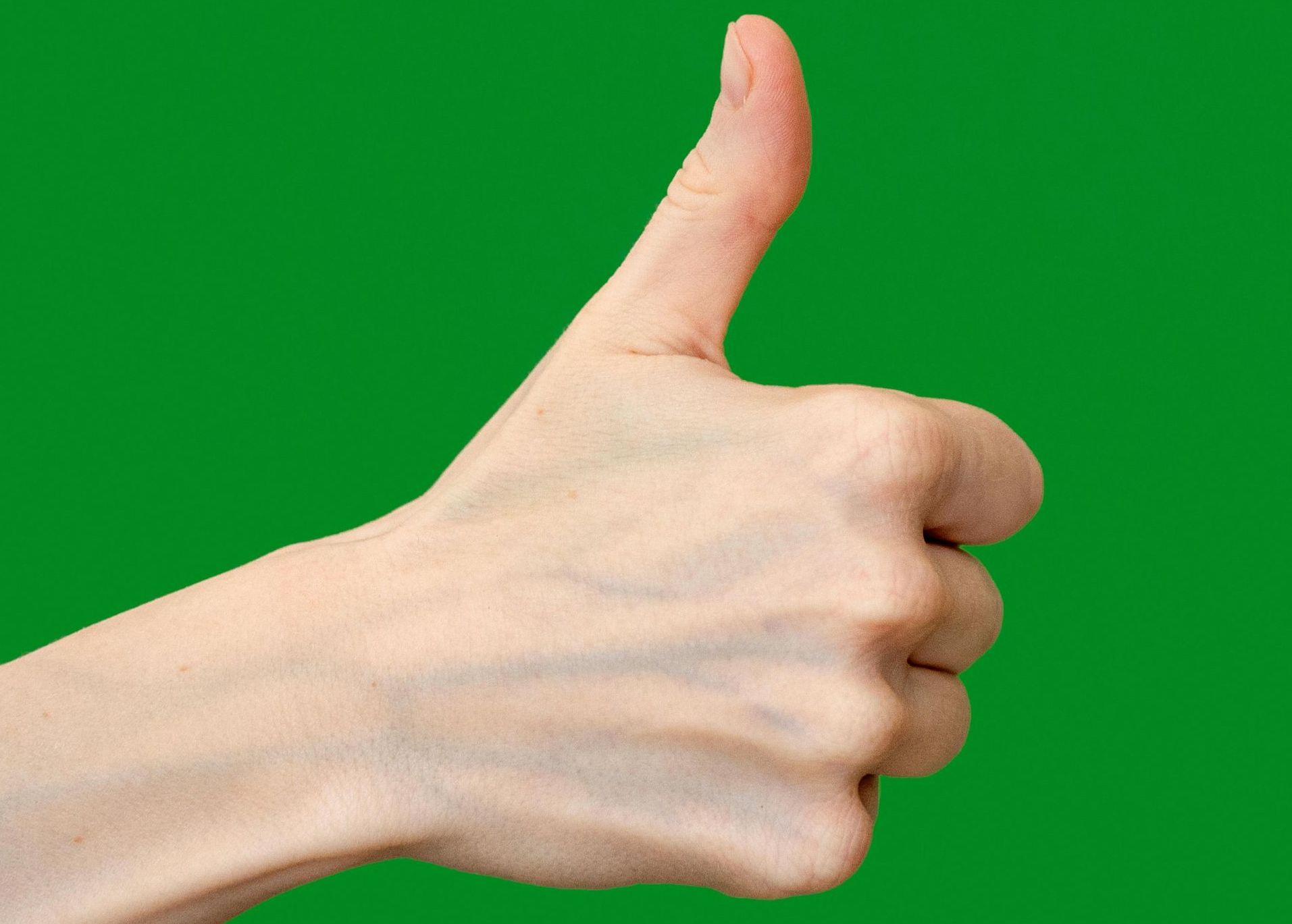 A hand is giving a thumbs up sign on a green background
