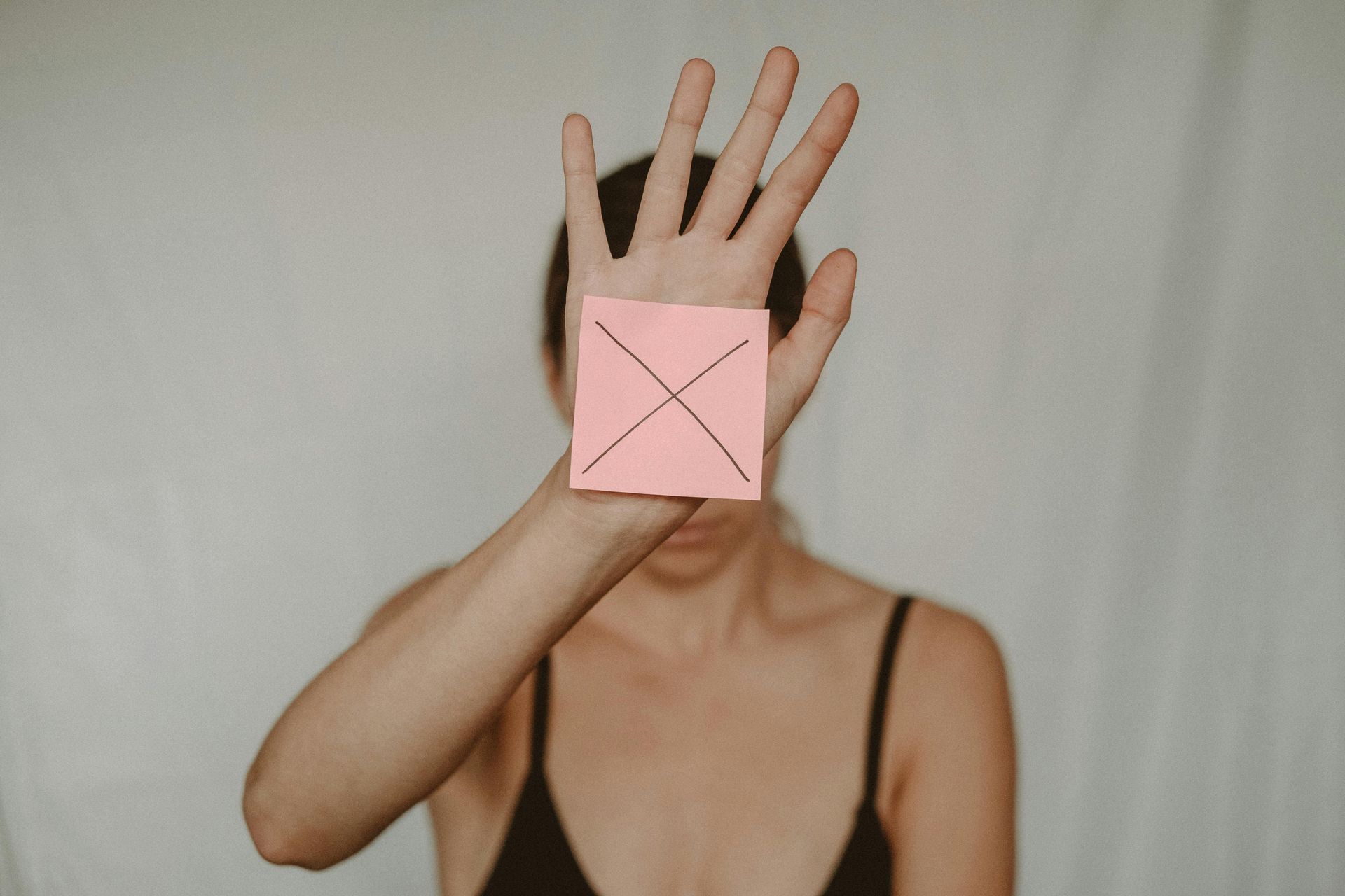 Roze 'geeltje' met een kruis erop. Vastgeplakt op de binnenkant van de rechterhand van een vrouw.