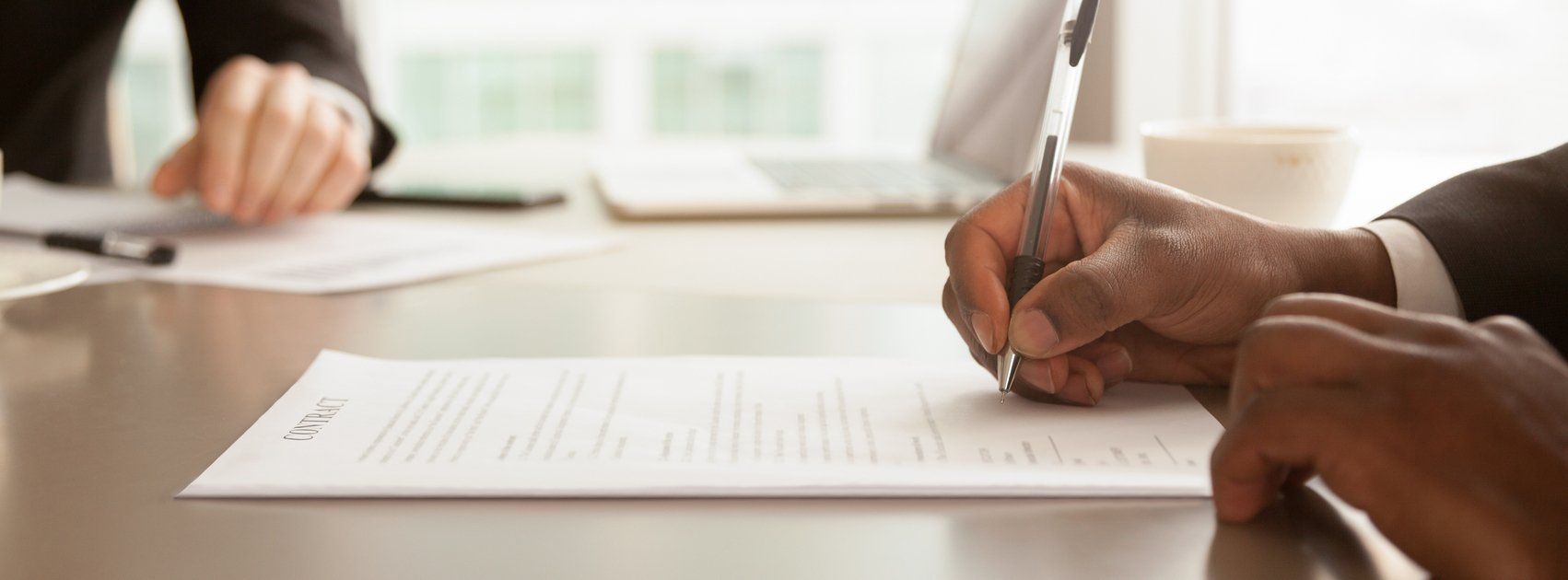 afrikaanse zakenman zitten aan het bureau met pen ondertekent (vaststellings)overeenkomst