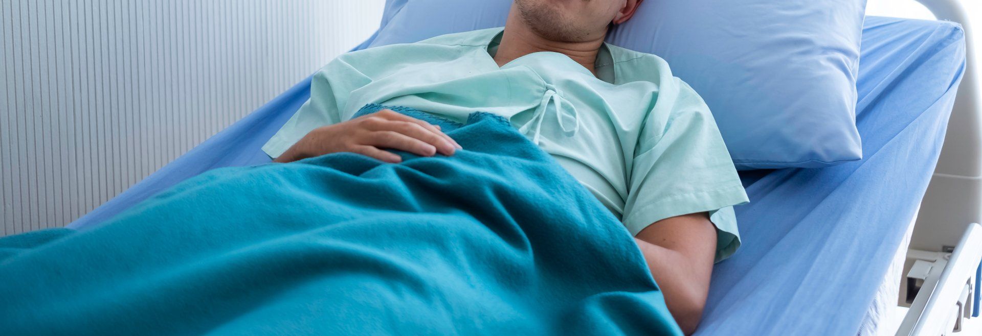 patiënt ligt op een bed met blauw beddengoed  in het ziekenhuis