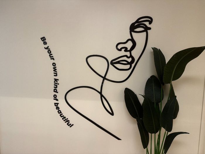 Minimal black line-art face with plant leaves and the phrase “be your own kind of beautiful.”