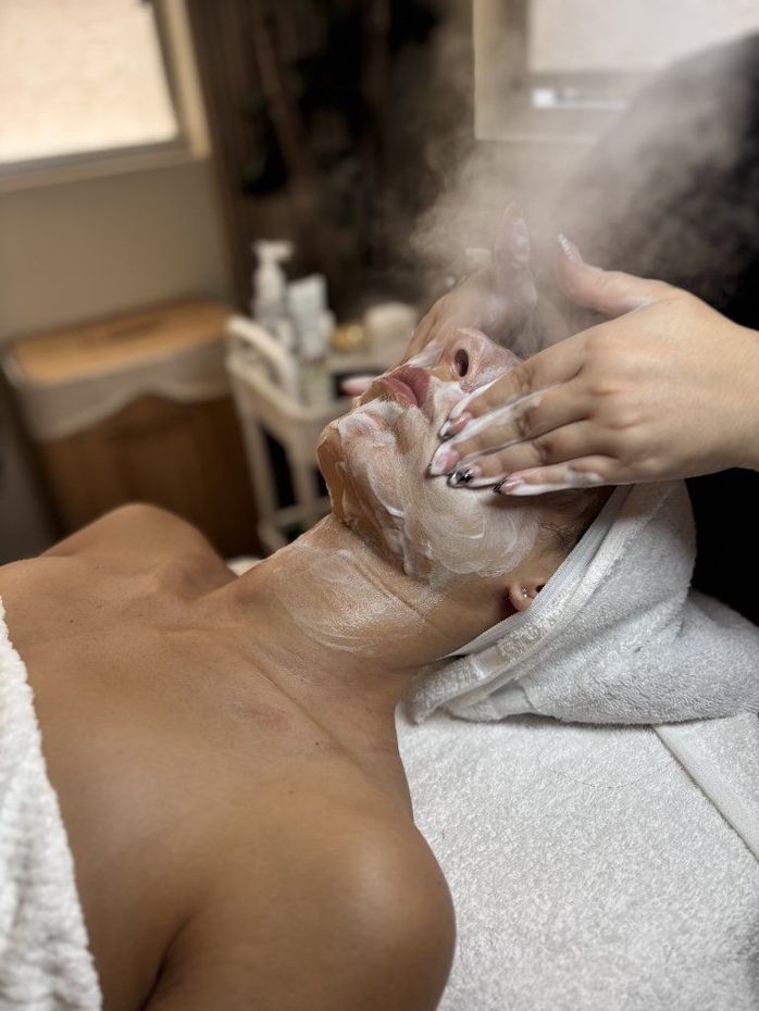Spa treatment with a person receiving a facial massage and foam on their face