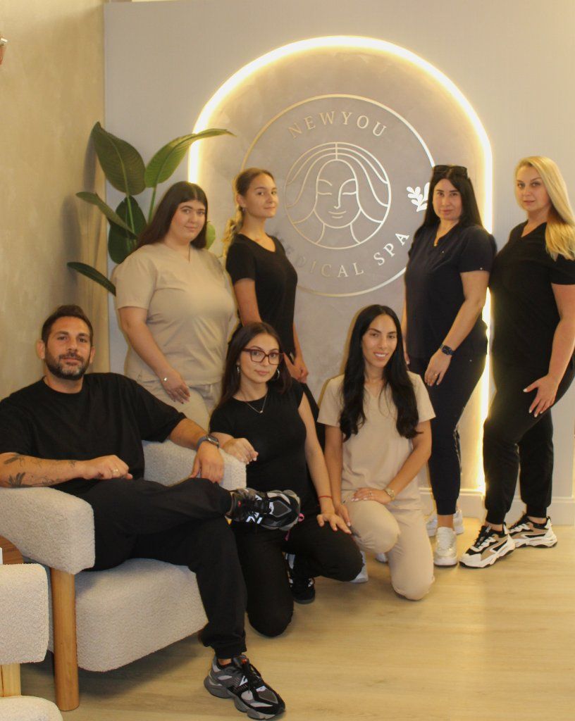 Seven people posing in a modern office lounge with a glowing circular wall logo behind them.