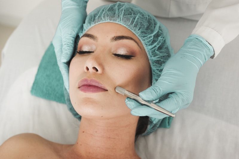 Cosmetic procedure on womanβs face with gloved hands applying filler near her lips