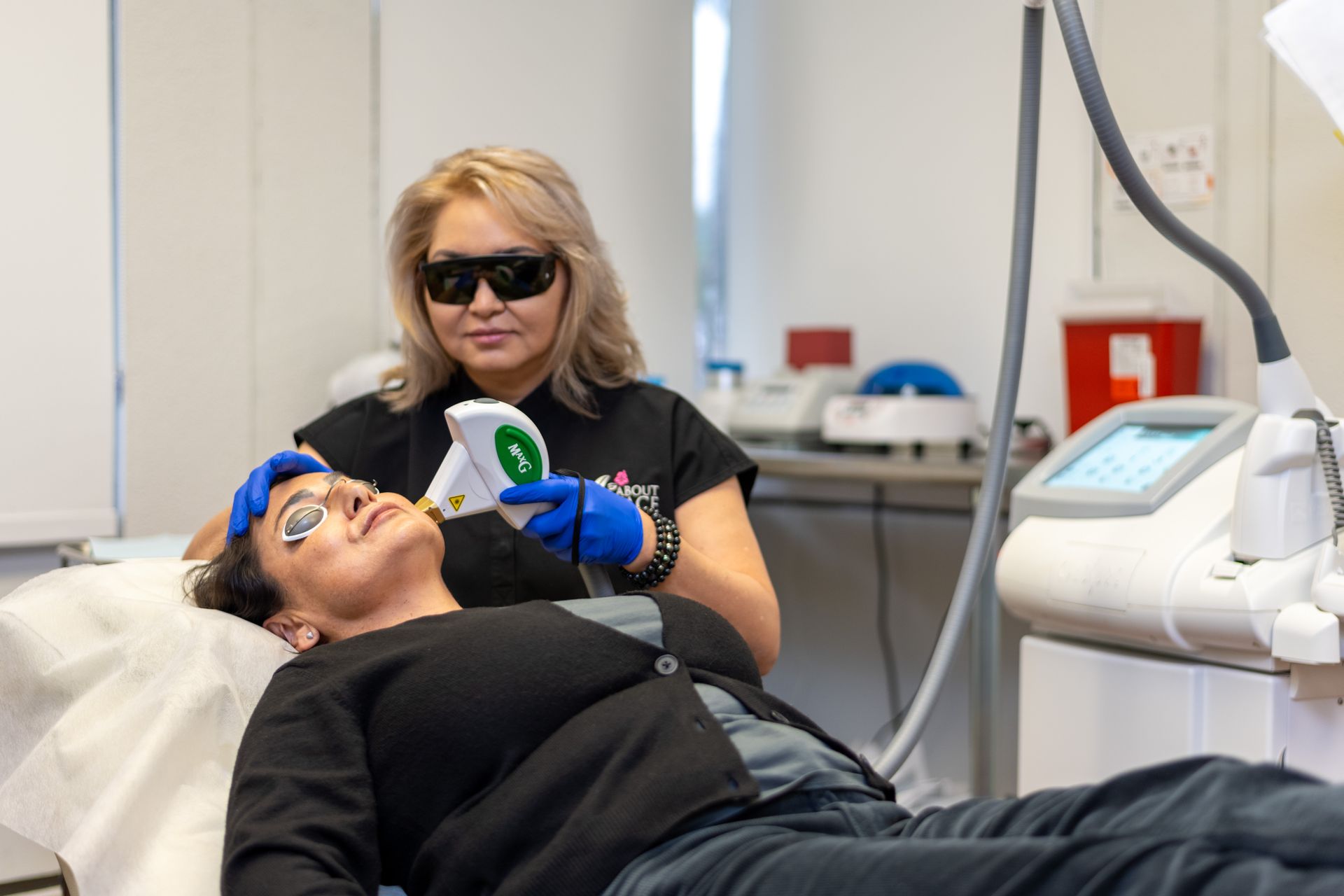 a woman is laying on a bed getting a laser treatment on her face