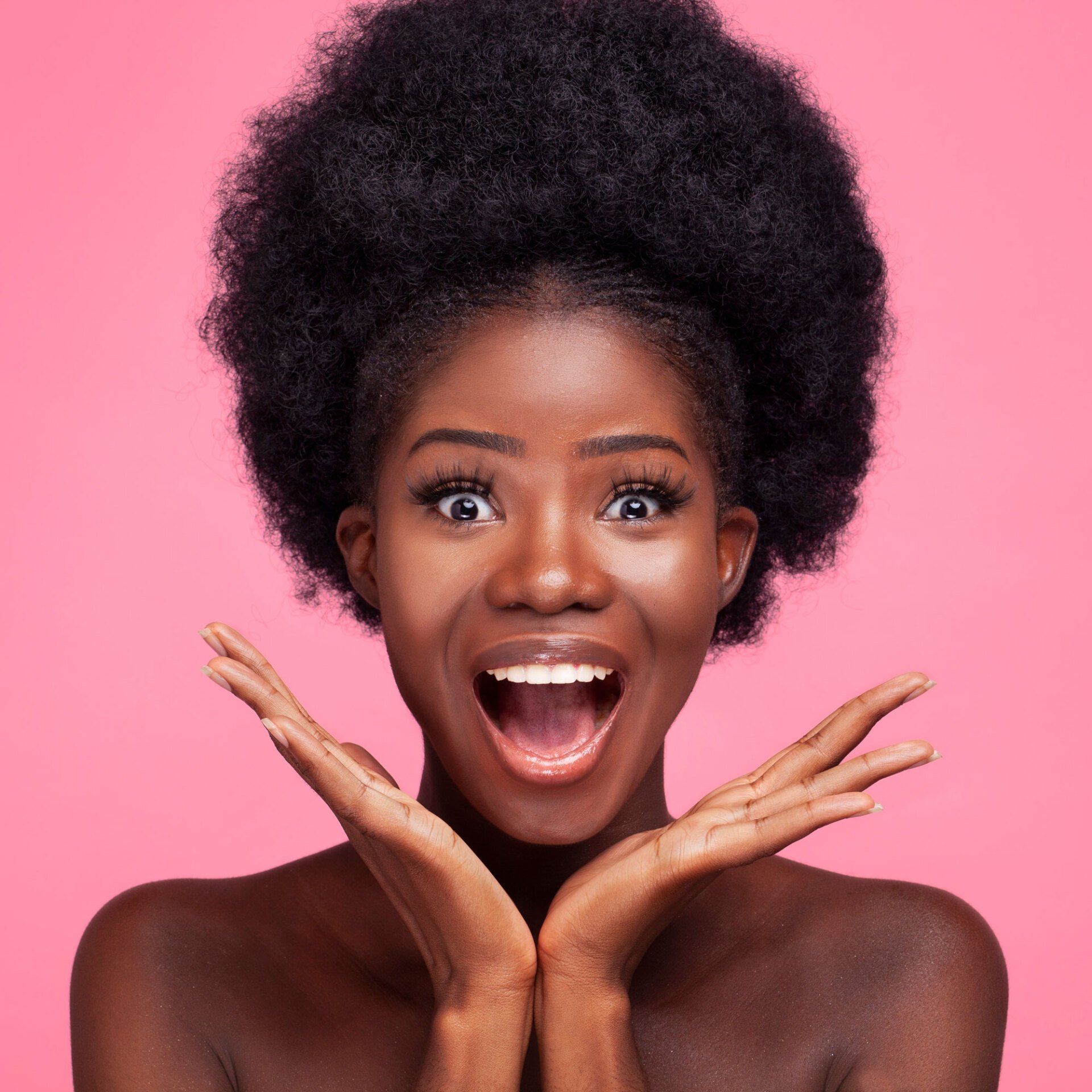Black woman looking happy and surprised smiling at the camera