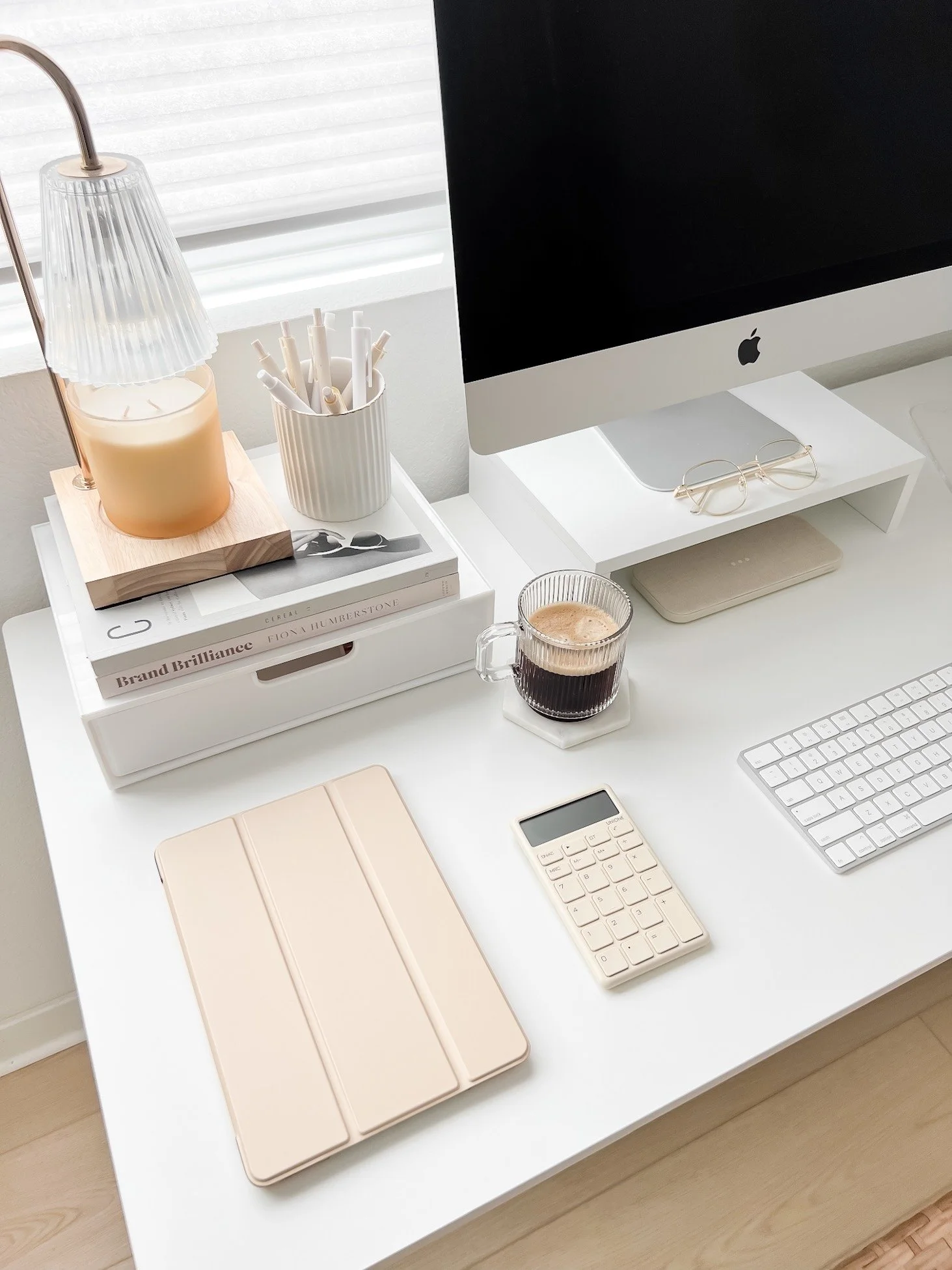 White desk with computer, coffee, and office supplies.
