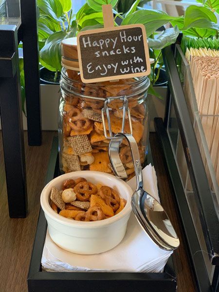 A jar and bowl of snack mix on a tray with a chalkboard sign reading 