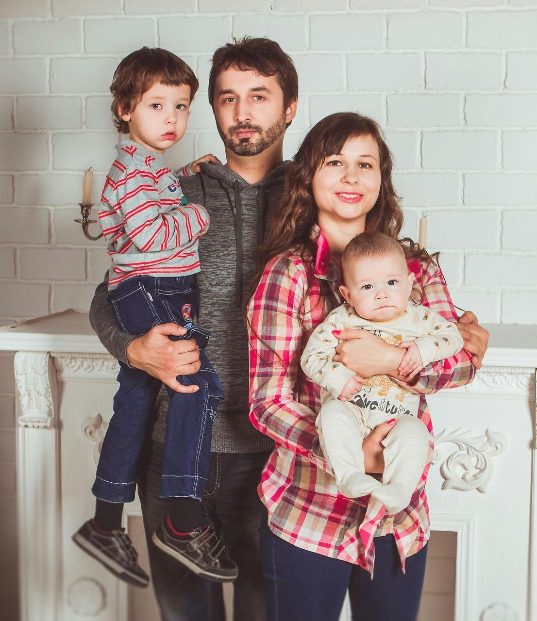A family is posing for a picture in front of a fireplace.