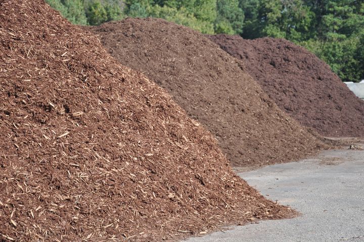 Large piles of mulch on the side of the road