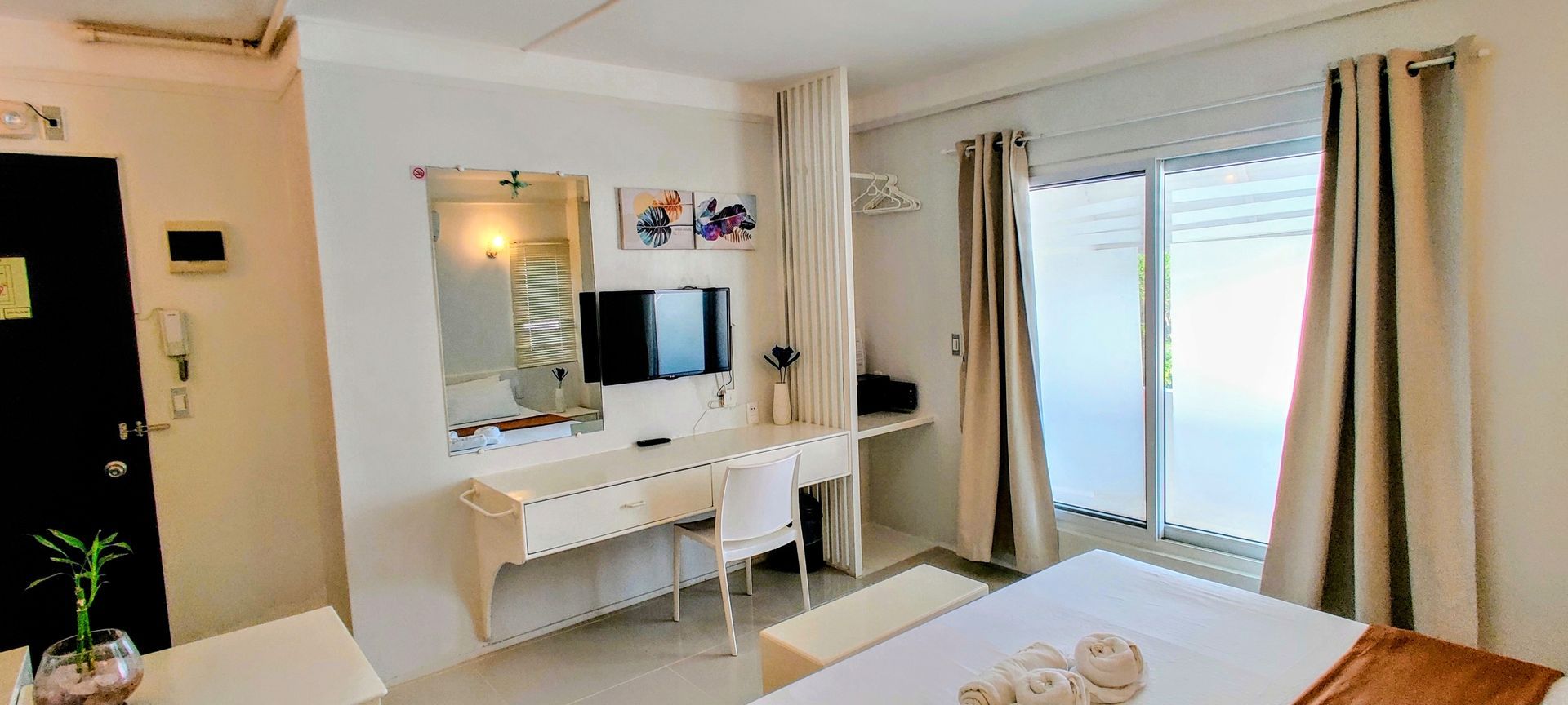 A motorcycle is parked in front of a building with a fence surrounded by plants.