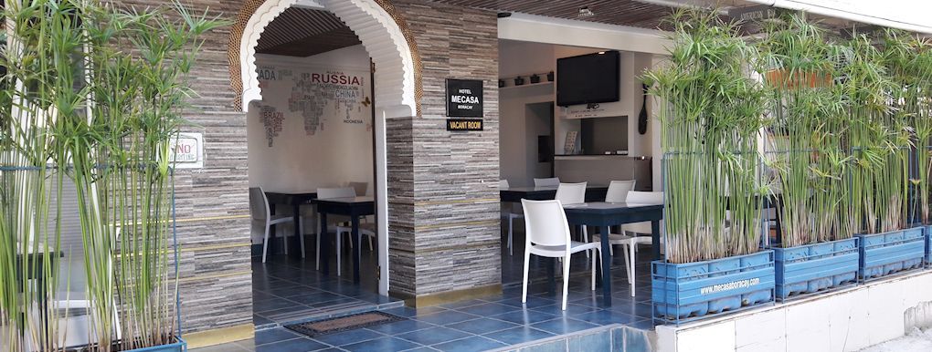 A restaurant with tables and chairs in front of a stone wall.