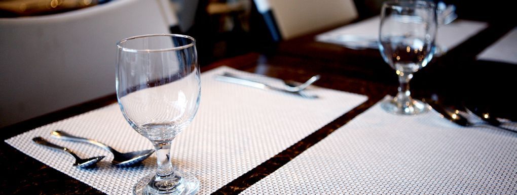 A wine glass is sitting on a placemat on a table.