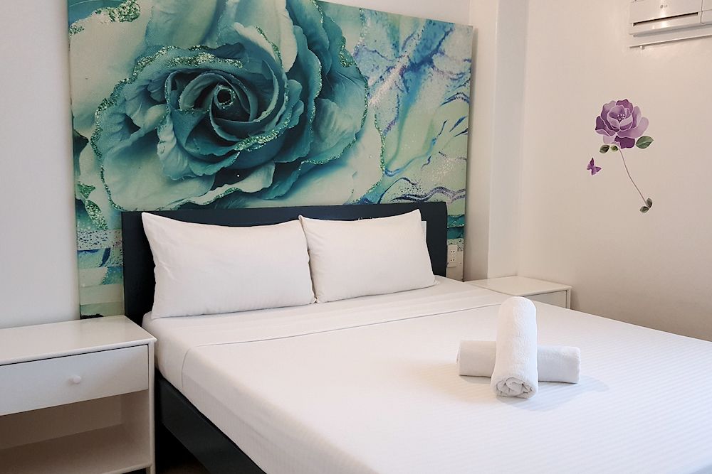 A bedroom with a bed and a picture of a rose on the wall