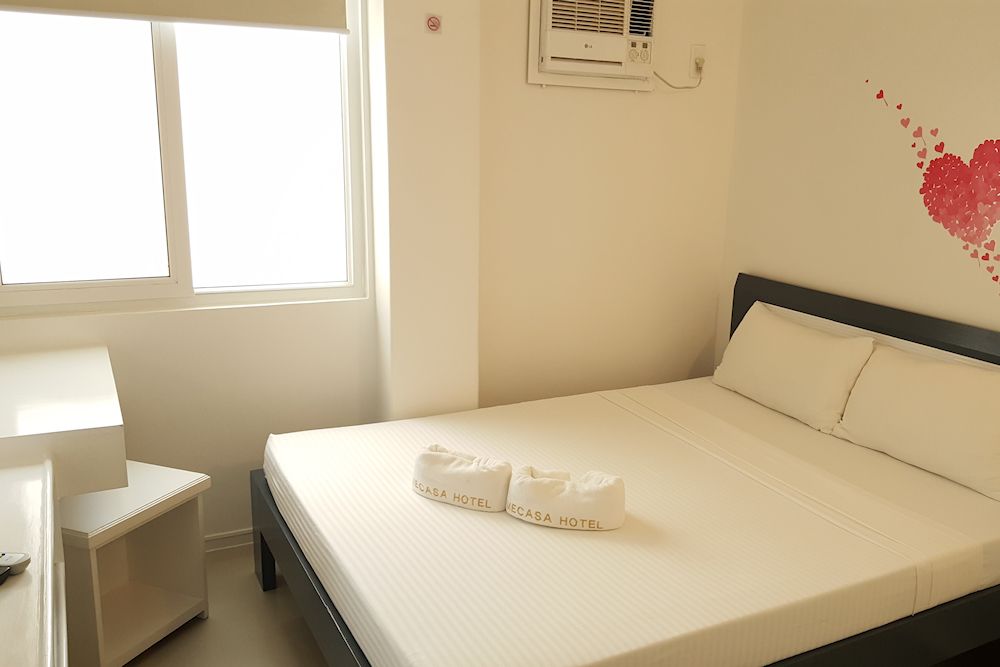 A bedroom with a bed and a window with a heart on the wall.