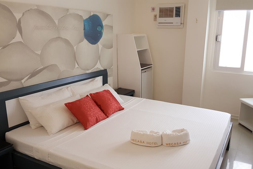 A hotel room with a king size bed and a window.