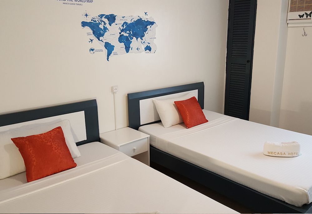 A bedroom with two beds and a map of the world on the wall.