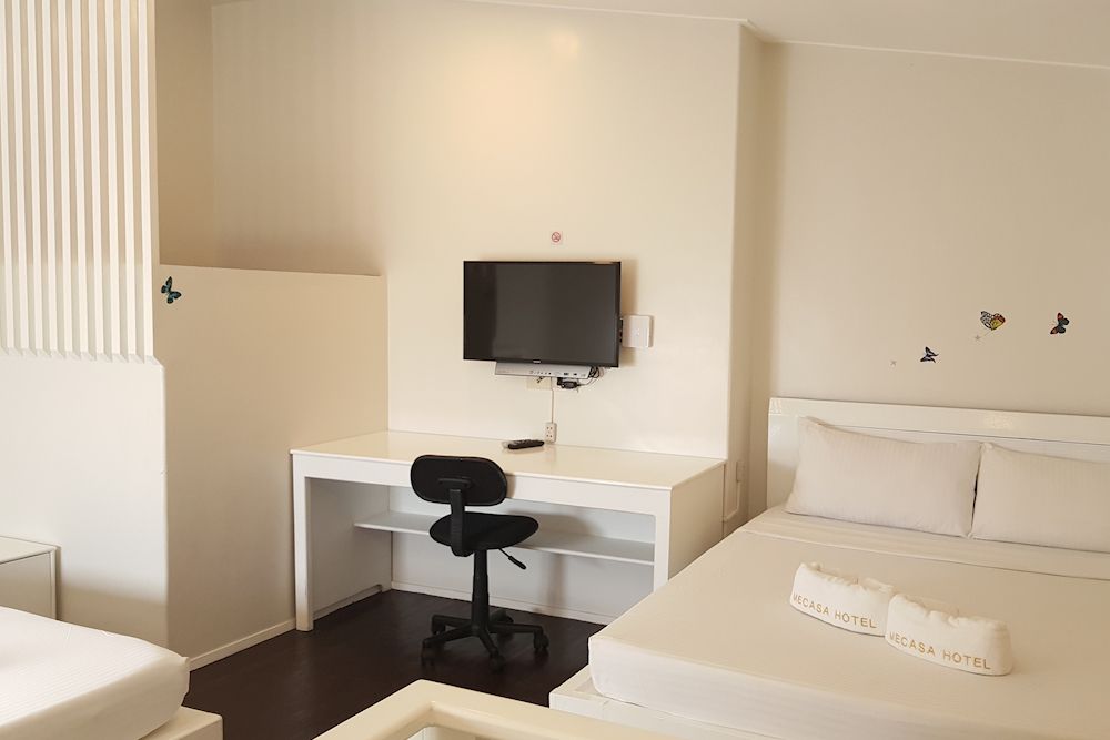 A hotel room with two beds , a desk and a television.