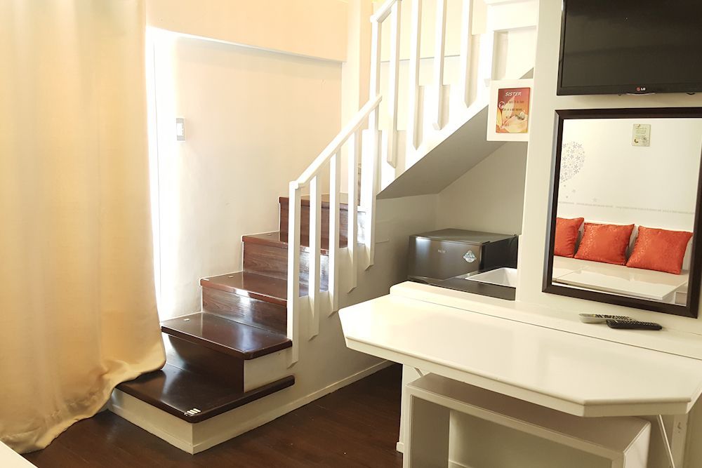 A room with stairs , a desk , a television and a mirror.
