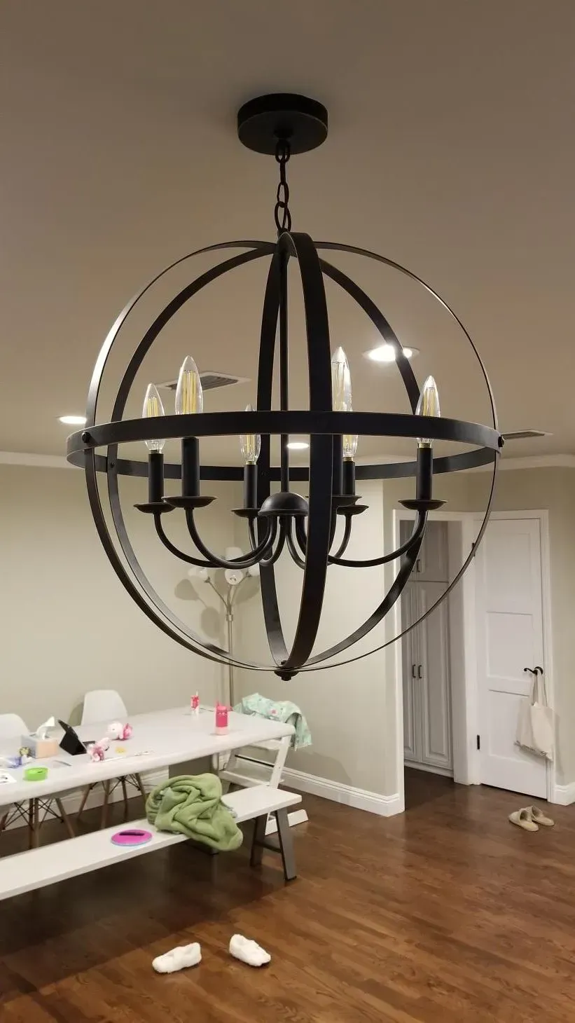 Black orb chandelier lighting installation in dining room