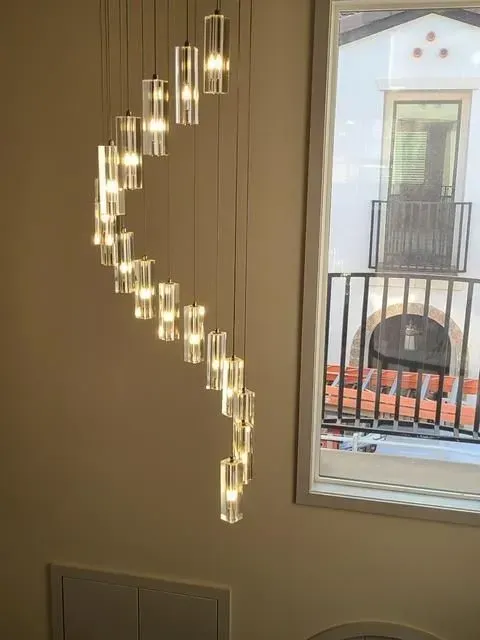 Curved cascading pendant lights glowing beside a window in a modern interior