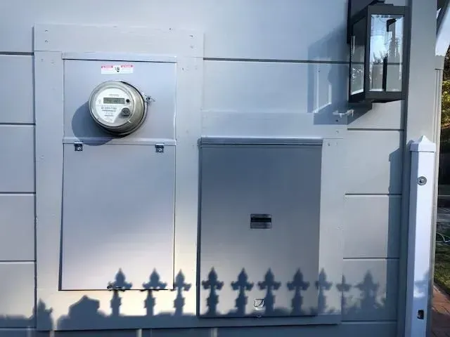 Gray utility boxes and a round electric meter mounted on a building wall.