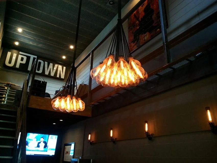 Dim restaurant interior with hanging pendant lights and an “UPTOWN” sign