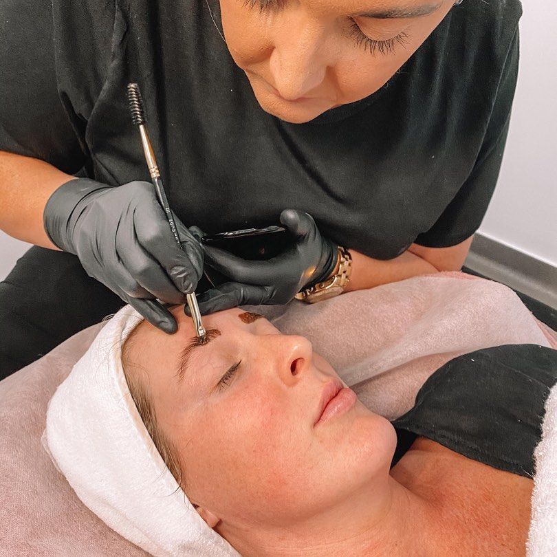 A woman is laying on a bed getting her eyebrows painted -  Beauty & Laser by Sarah in Long Jetty, NSW