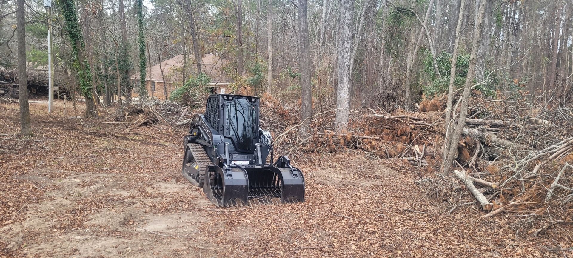A black tractor is driving through a lush green forest.