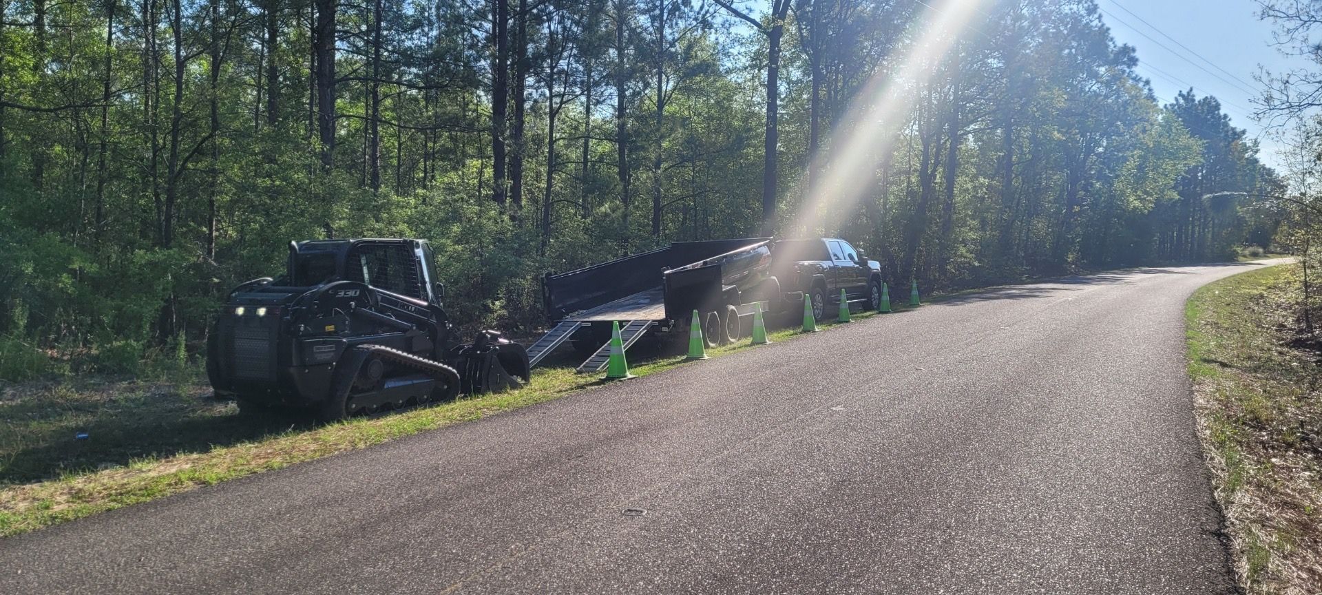 A bulldozer is parked on the side of a road next to a forest.